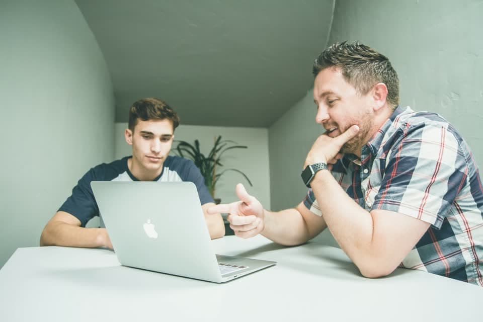 Two colleagues discussing a deal at a laptop