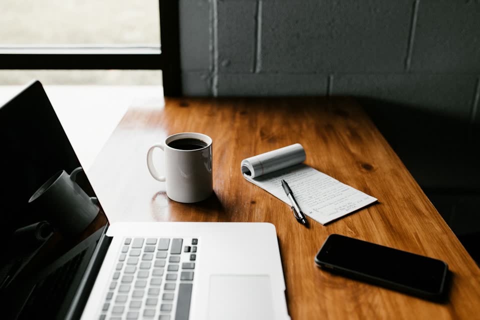 A laptop and a notebook on a wooden desk